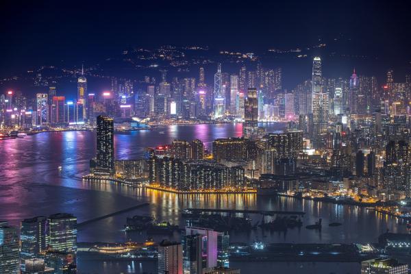 Cityscape of Hong Kong at night, night lights and tall buildings around a lake.