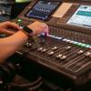 A students hands operating the control board in the tv studio